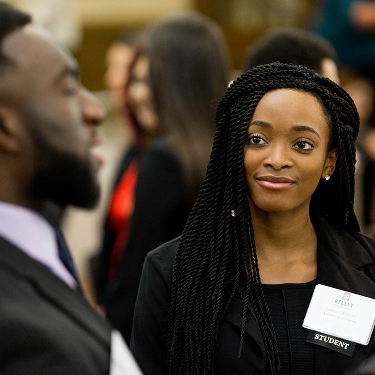 A student listens to another person speak at a career fair.